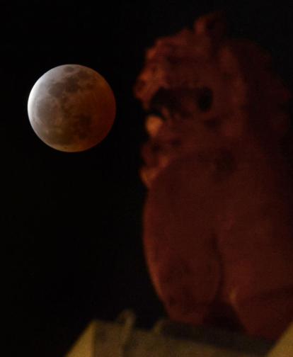A lunar eclipse is observed above a lion-shaped statue in Urasoe city, Okinawa prefecture, southern Japan, Saturday, April 4, 2015. (AP Photo/Kyodo News) JAPAN OUT, MANDATORY CREDIT